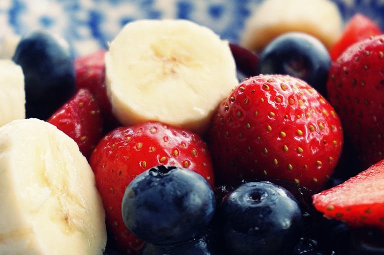 Close-up of fresh bananas, strawberries, and blueberries. Perfect for health and diet themes.